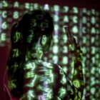 Tela de computador exibindo código e interfaces digitais em ambiente escuro, evocando vigilância tecnológica