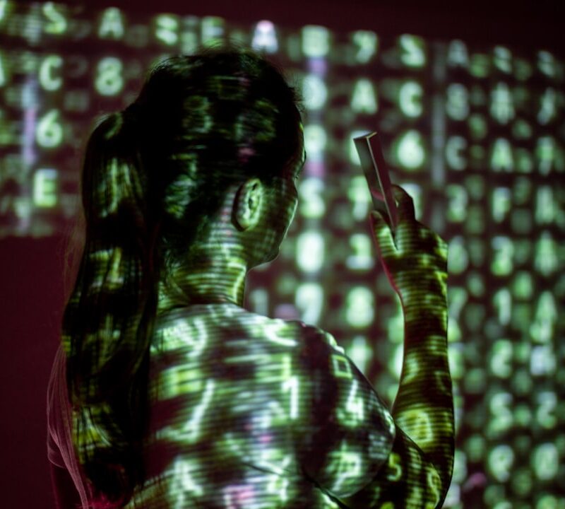 Tela de computador exibindo código e interfaces digitais em ambiente escuro, evocando vigilância tecnológica