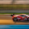 Carro esportivo em alta velocidade em rodovia ao entardecer, evocando a atmosfera de jogos de corrida em mundo aberto.