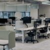 Escritório corporativo vazio com estações de trabalho, representando reestruturação empresarial